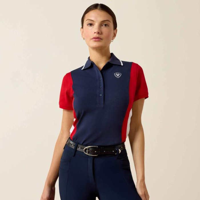 Woman wears navy and red polo t-shirt with breeches on a plain background