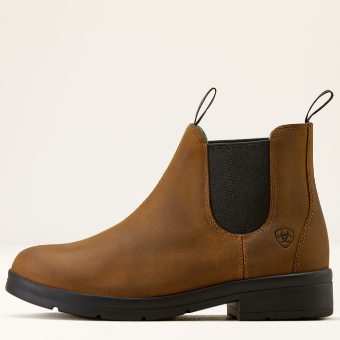 Brown leather boot with black sole on a beige background