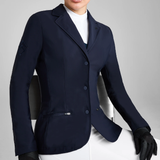 Person wearing a navy blue blazer and holding a horse riding helmet on a light grey background