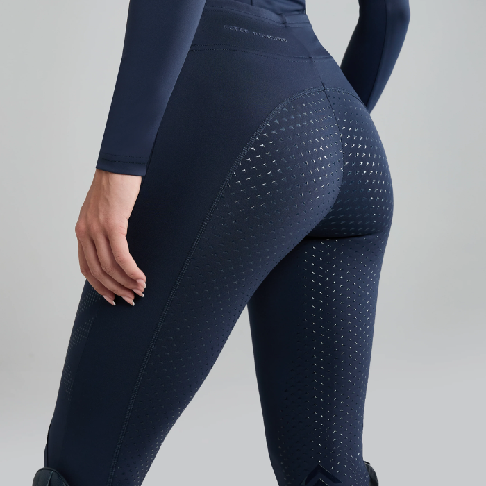Navy blue riding pants with textured design on a grey background