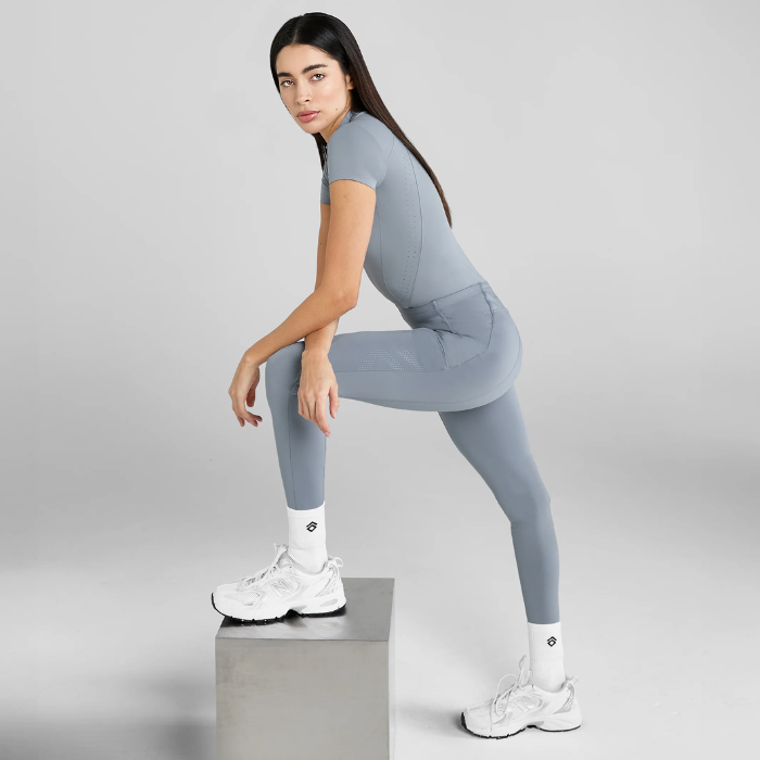 Woman in blue athletic outfit posing on a light grey background