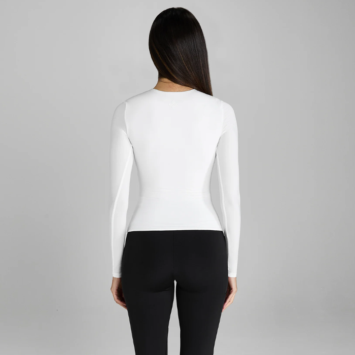 Person wearing a white long-sleeve top and black leggings on a grey background