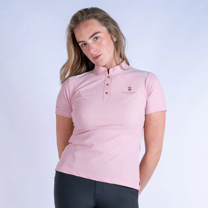 Woman wearing a pink polo shirt with a logo on a white background