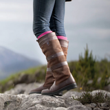 Brown knee-high boots with pink long socks worn on a rocky landscape
