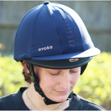 Person wearing a navy equestrian helmet with 'evoke' branding outdoors.