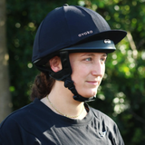 Person wearing a black riding helmet with 'evoke' branding against a blurred green background