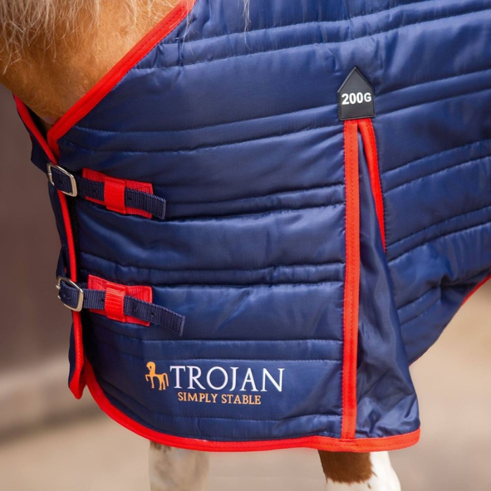 Blue horse blanket with red accents and Trojan branding on a blurred background