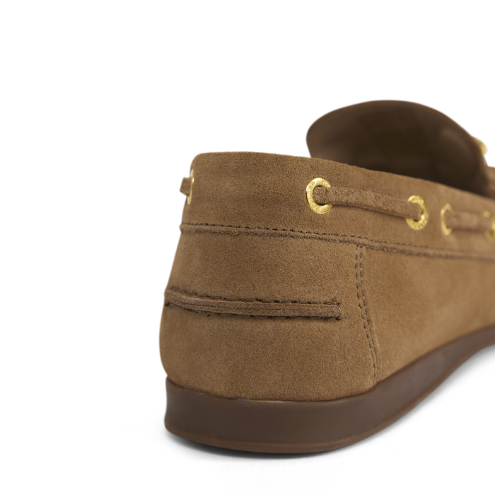 Brown suede shoe with gold eyelets on a white background