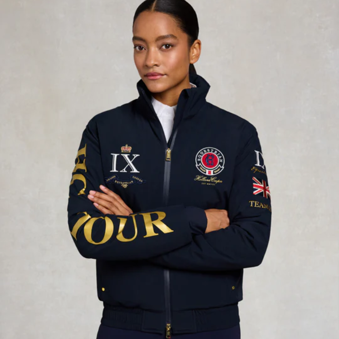 Person wearing a navy jacket with gold text and logos on a plain background