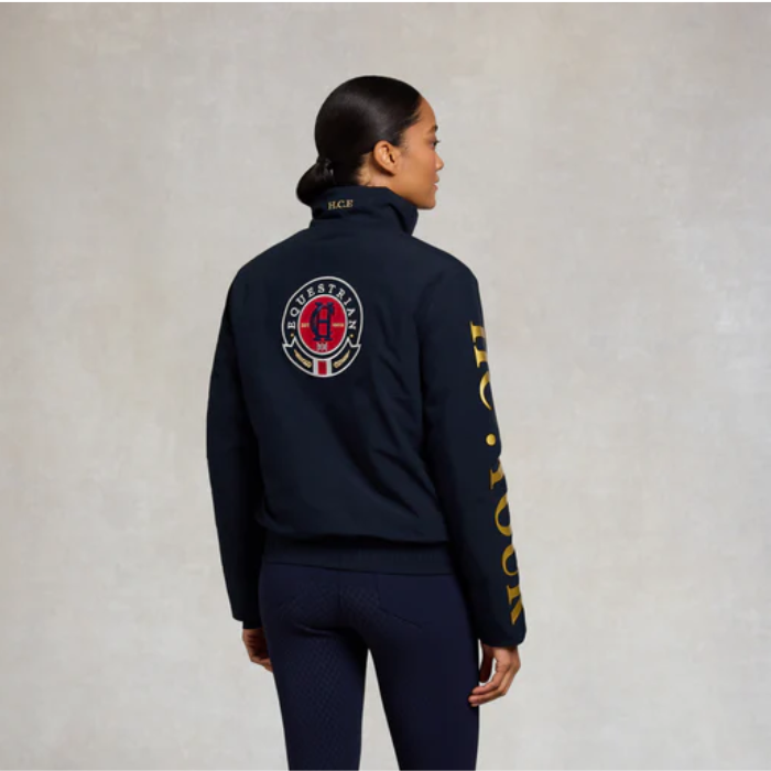 Person wearing a navy jacket with logos on a plain background