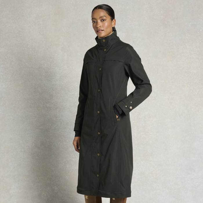 Woman wearing a dark raincoat against a neutral background