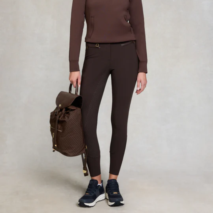 Person wearing brown outfit with backpack on plain background