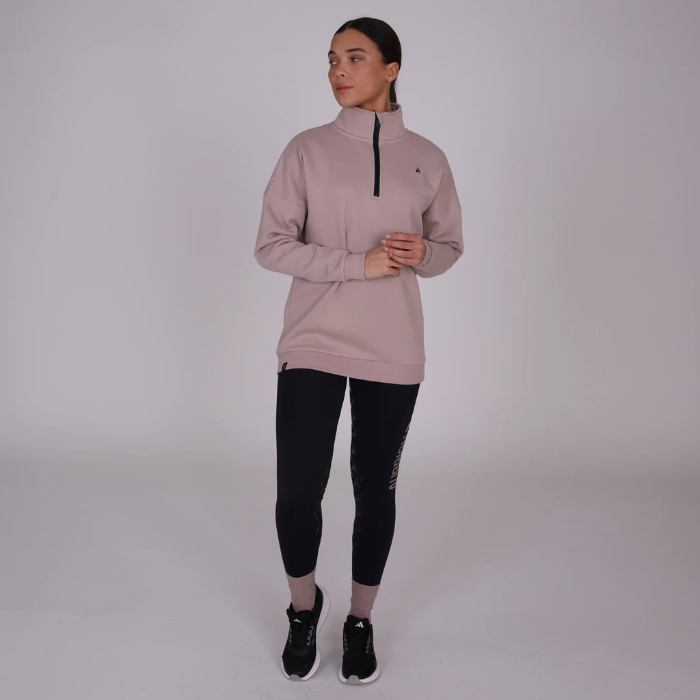 Woman wearing a beige athletic sweatshirt and black leggings on a white background