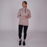 Woman wearing a beige athletic sweatshirt and black leggings on a white background