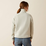 Person wearing a light gray fleece jacket and blue jeans on a beige background