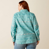 Woman wearing a teal patterned shirt against a beige background