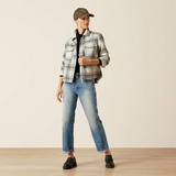 Person wearing a plaid shirt, jeans, and a cap on a plain background