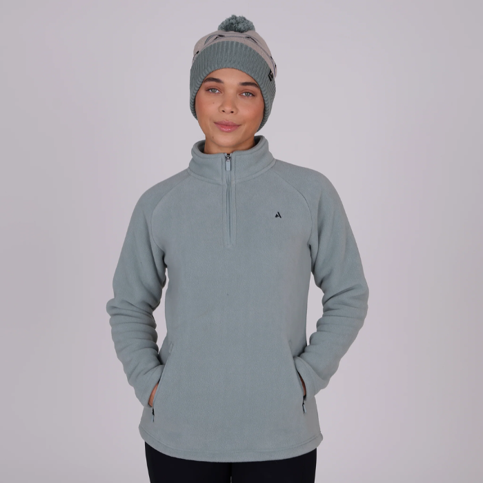 Person wearing a light blue pullover with a small logo and a matching beanie on a plain background