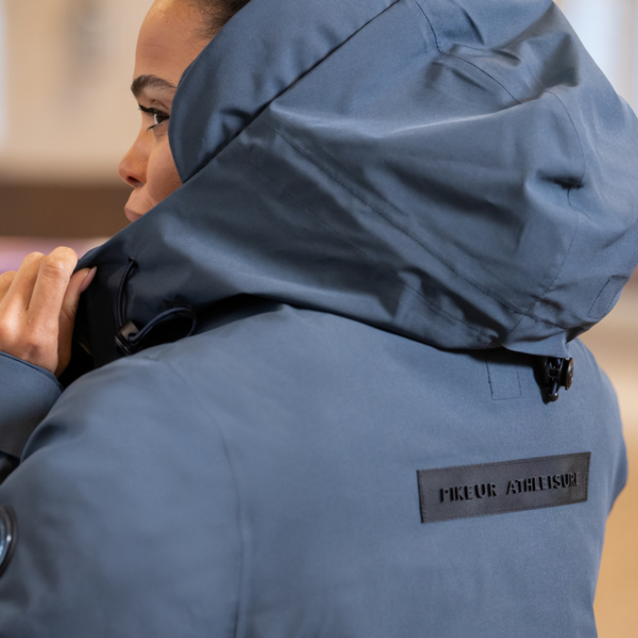 Person wearing a blue jacket with a brand label on the back