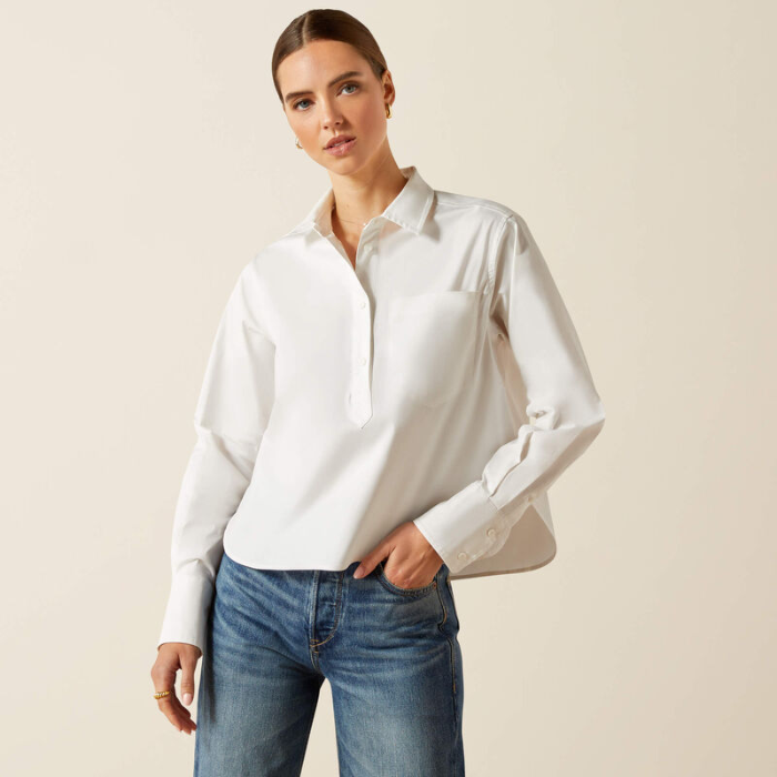 Woman wearing a white shirt and blue jeans against a beige background