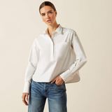 Woman wearing a white shirt and blue jeans against a beige background