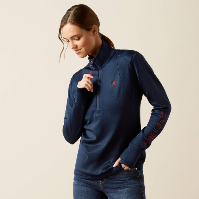 Woman wearing a navy blue pullover with red accents on a beige background
