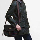 Person wearing a dark green jacket holding a black bag with plaid pattern on a light grey background