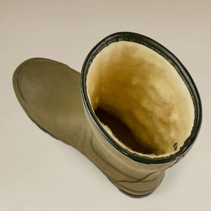 Green rubber boot with beige wool  interior on a beige background
