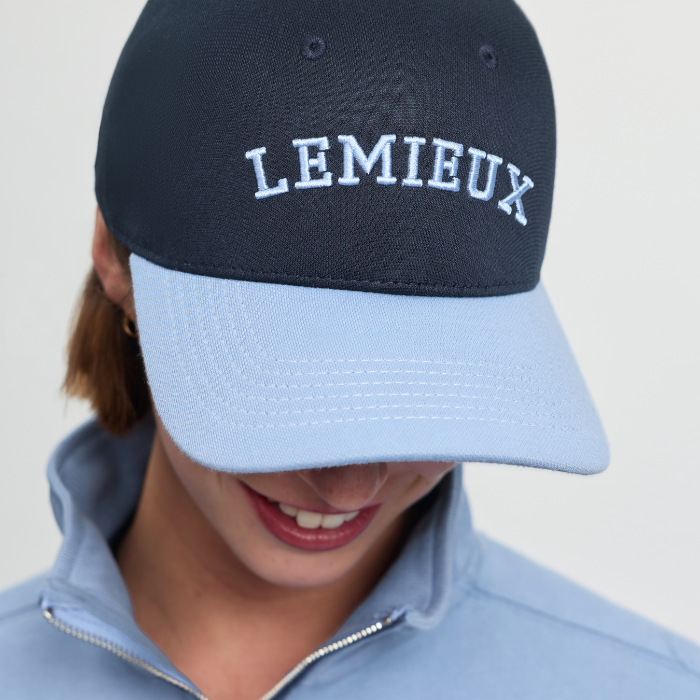 Person wears a navy blue cap with light blue peak and varsity-style LEMIEUX logo on a plain background