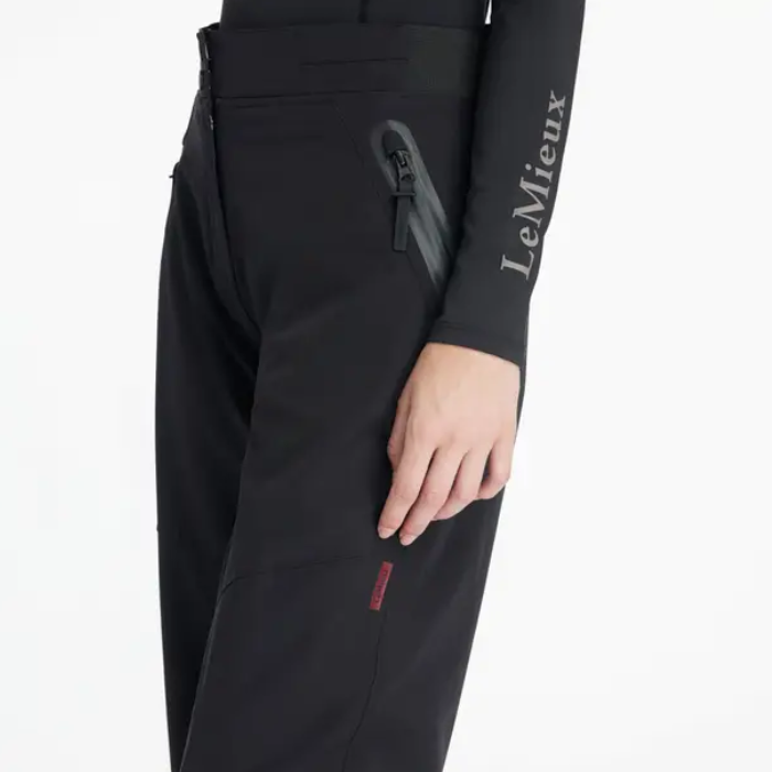 Close-up of black waterproof trousers and black long sleeved top with LeMieux branding