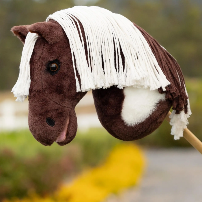 Brown and white toy hobby horse in a blurred outdoor setting