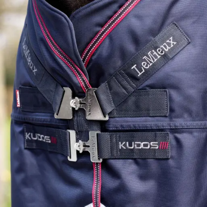 Front closure of a navy blue turnout rug with LeMieux and KUDOS branding