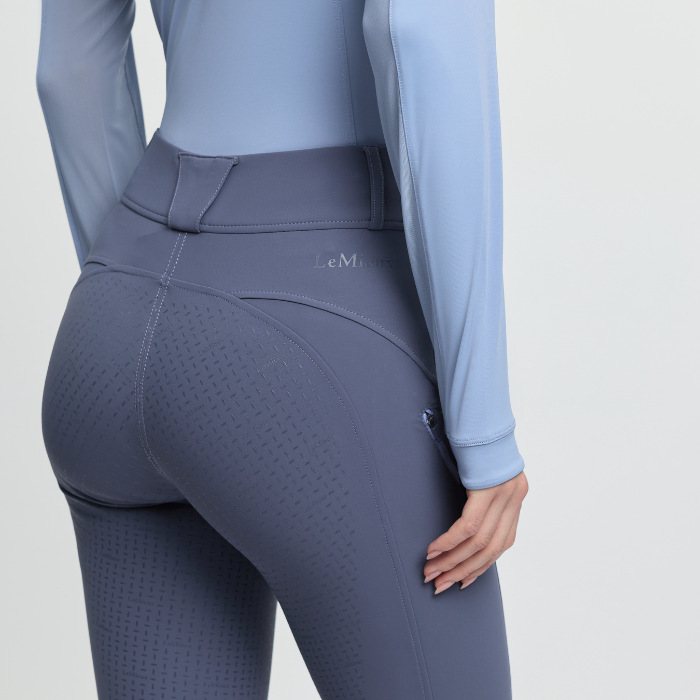 Person wearing a light blue long-sleeve top and grey-blue leggings on a light grey background