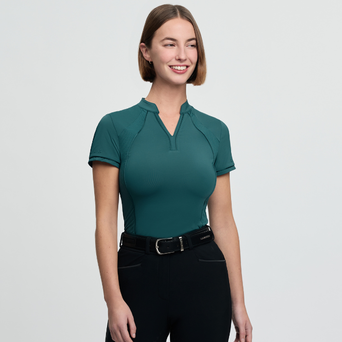 Woman wearing a teal short-sleeve top and black leggings on a light grey background