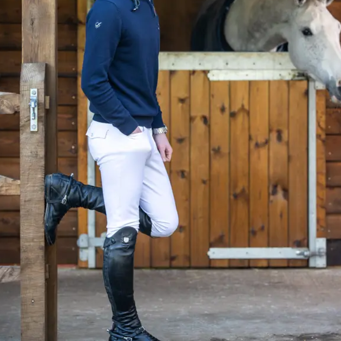 Man wears a pair of white riding breeches and long black boots on a stable yard