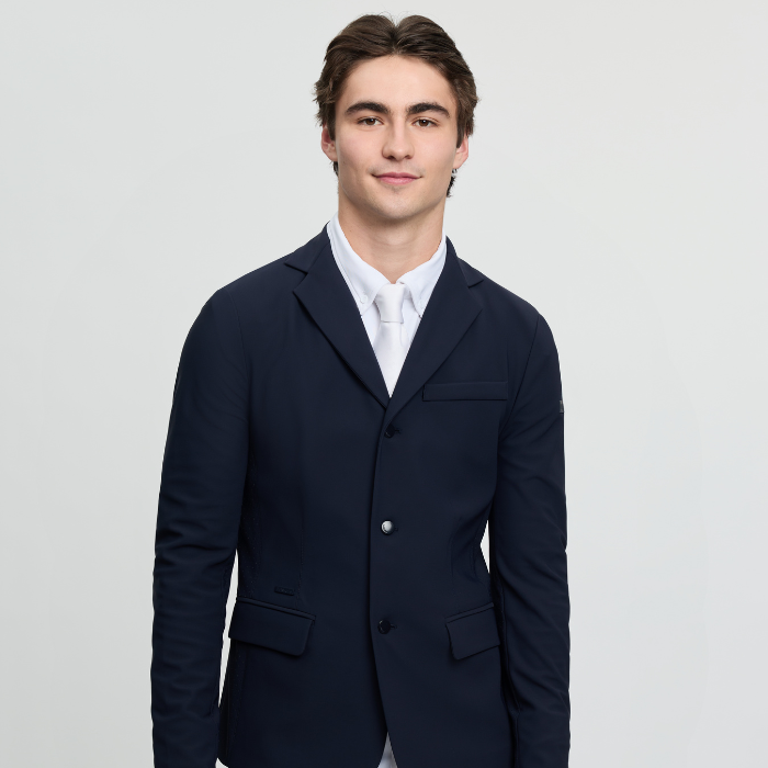 Man wears a navy smart jacket with white tie on a grey background