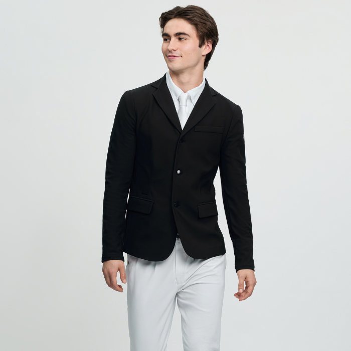 Man wears a black smart jacket with white breeches on a grey background