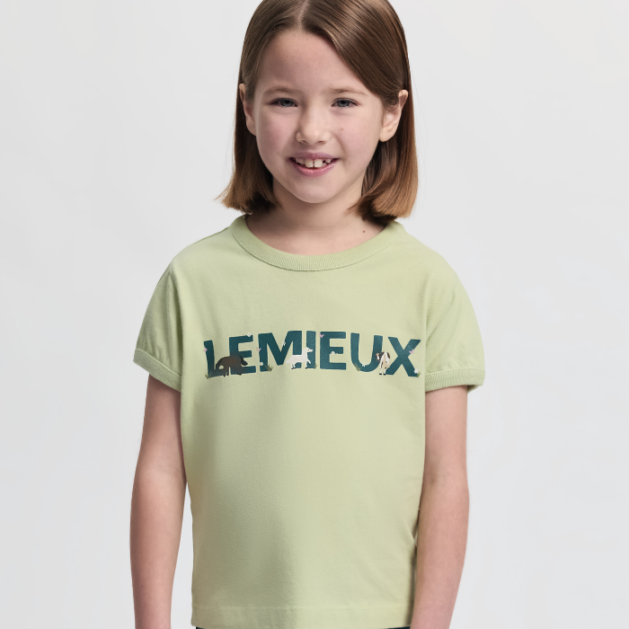 Young girl wearing a light green t-shirt with 'LEMIEUX' printed on it against a plain background