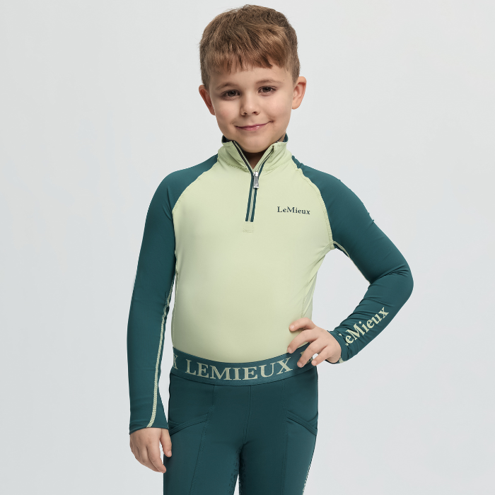 Child wearing a green and light green LeMieux outfit on a white background