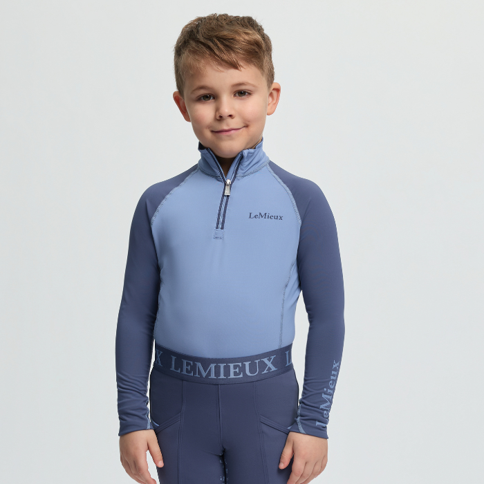 Child wearing a blue and navy equestrian outfit with 'LeMieux' branding on a light grey background