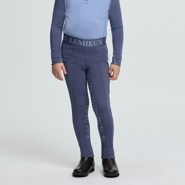 Person wearing blue equestrian leggings with 'Lemieux' branding on a white background