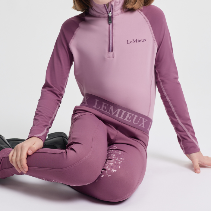 Person wearing a pink LeMieux outfit sitting on a white background