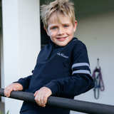 Young boy wearing a navy blue sweatshirt with a brand logo, standing outdoors.
