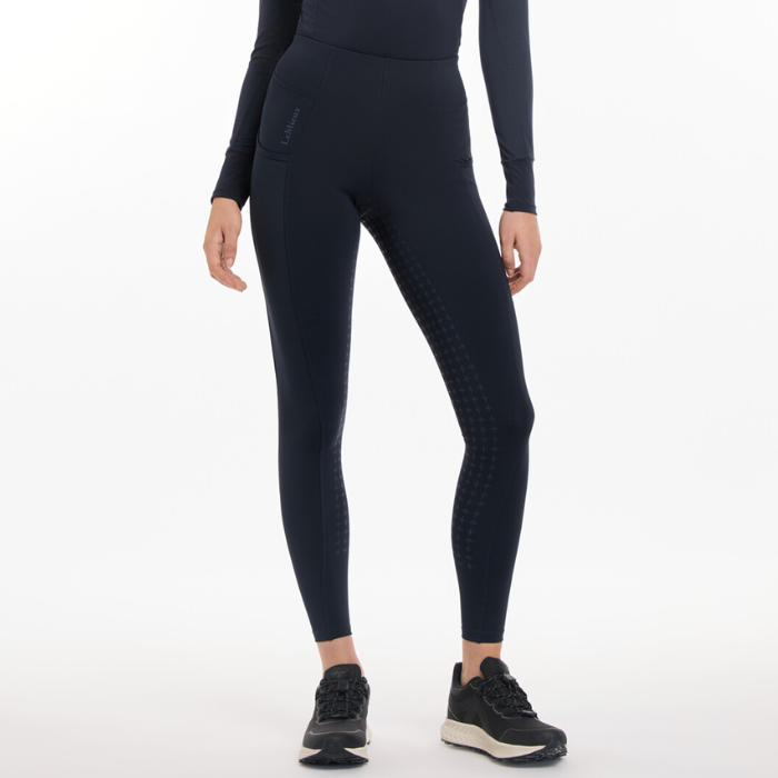 Person wearing navy riding leggings on a grey background