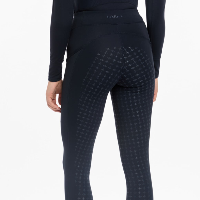 Person wearing navy riding leggings with grip pattern on a grey background