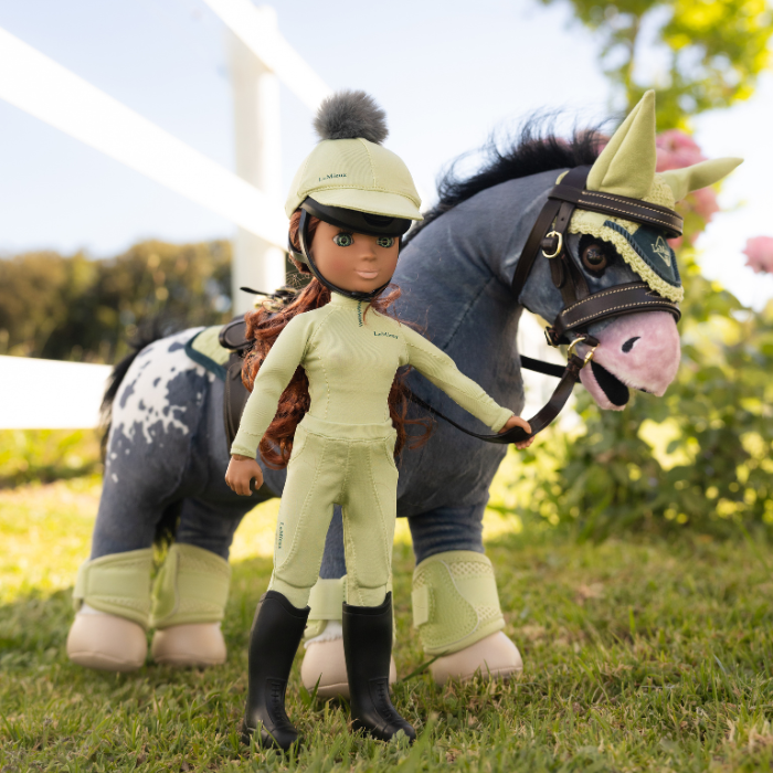 Plush horse with a rider doll in a yellow outfit on a grassy field with flowers.