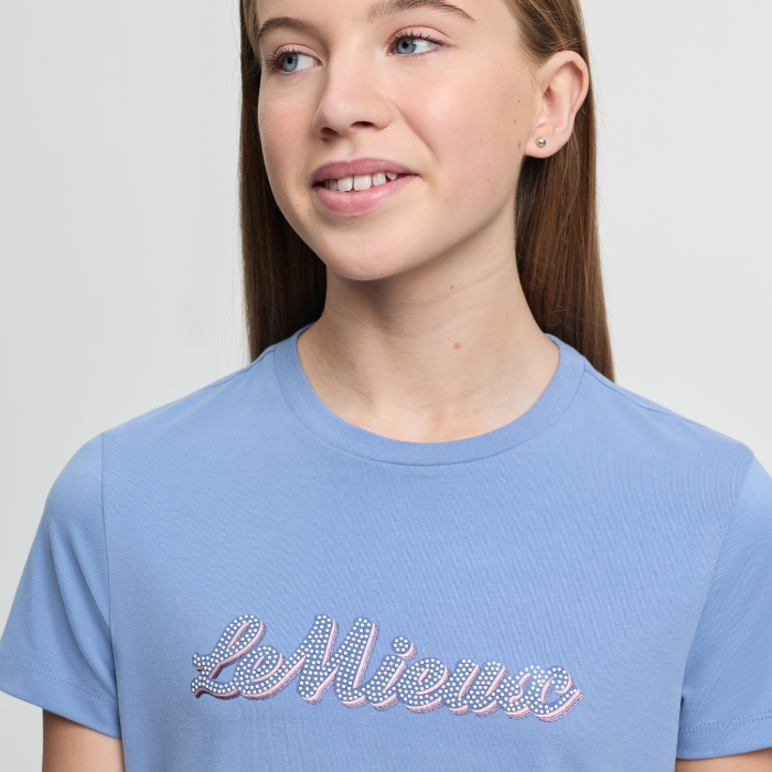 Girl wearing a light blue t-shirt with 'Le Mieux' text on a plain background