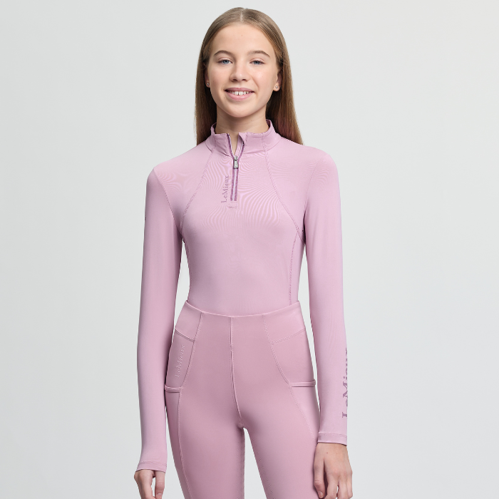 Person wearing a pink equestrian outfit suit on a light grey background