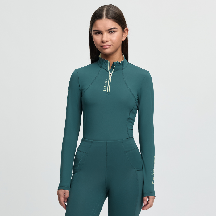 Person wearing a teal equestrian outfit with a white background