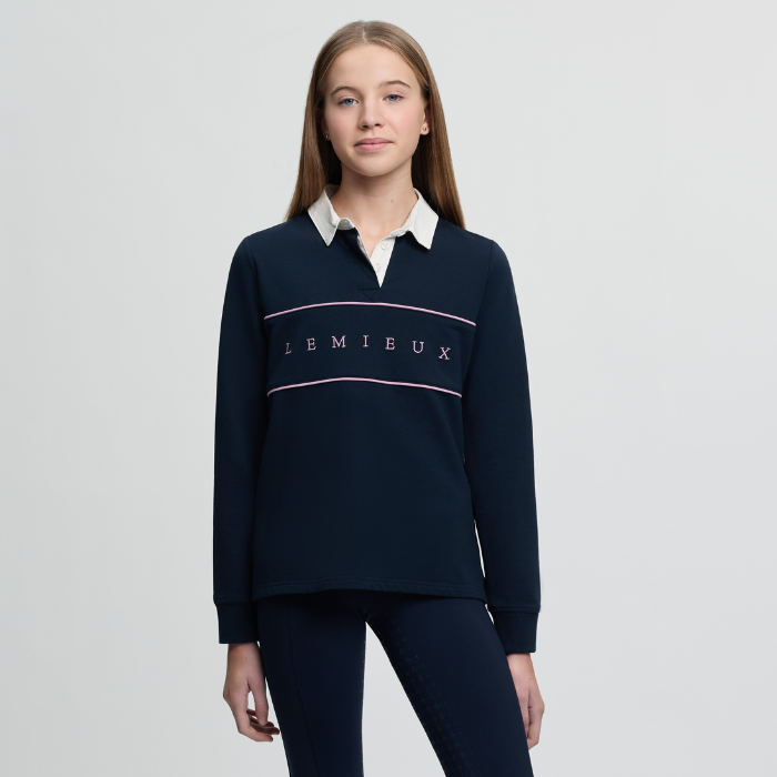 Person wearing a navy blue Lemieux sweater with a white collar on a light grey background